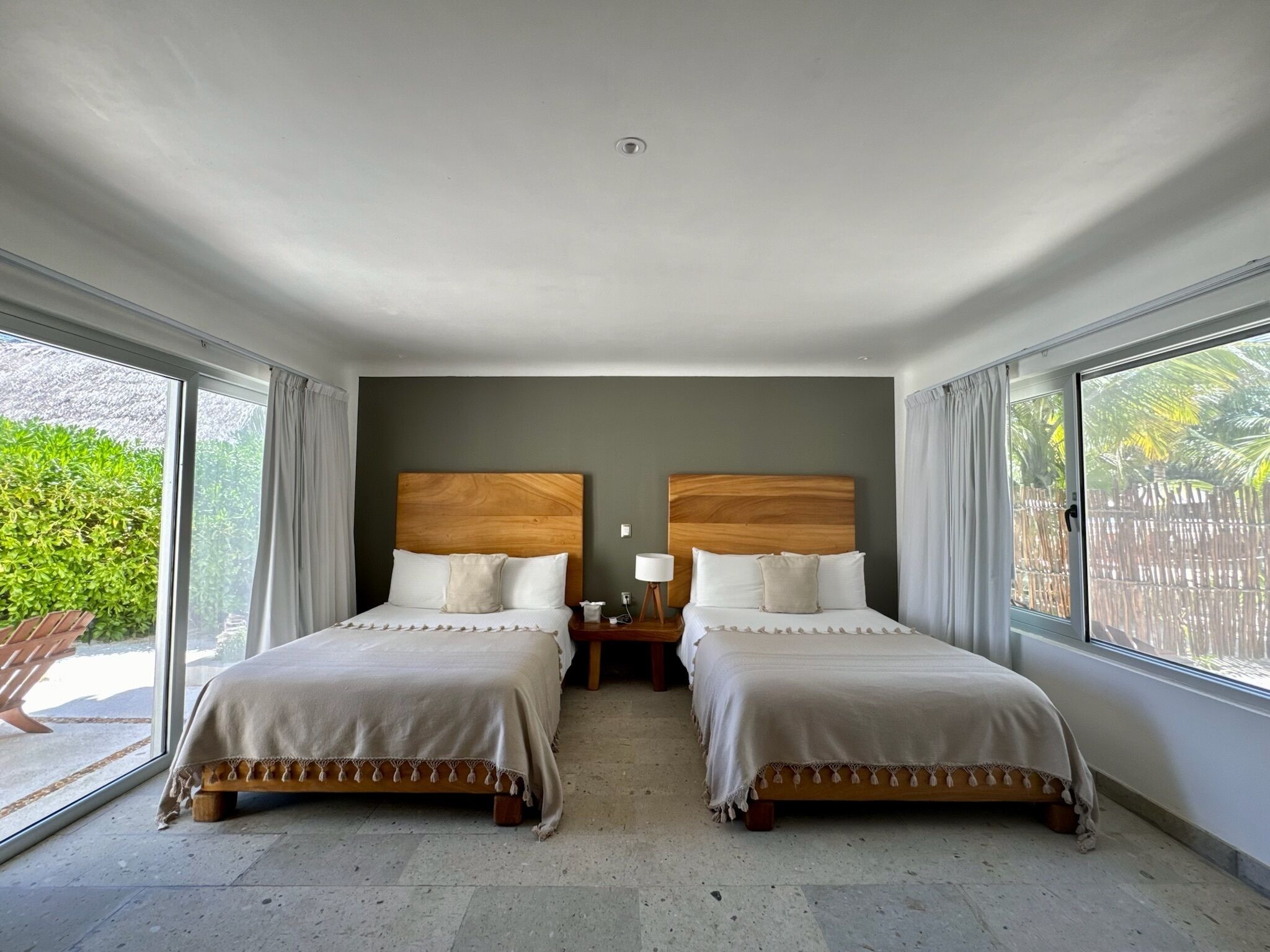Habitación de hotel con dos camas, una mesita de noche y una ventana con vista a áreas verdes.