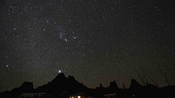 A starry night sky over a mountainous landscape with a visible mountain peak.