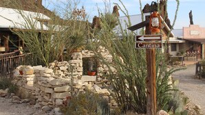 A rustic stone wall with a wooden signpost indicating 'Cantina' to the left.