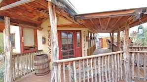 A rustic wooden building with a porch, a barrel, and signs reading "TAQUERIA" and "CERVEZA".