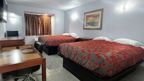 Habitación de hotel con dos camas, un escritorio, una silla, un televisor y un cuadro en la pared.