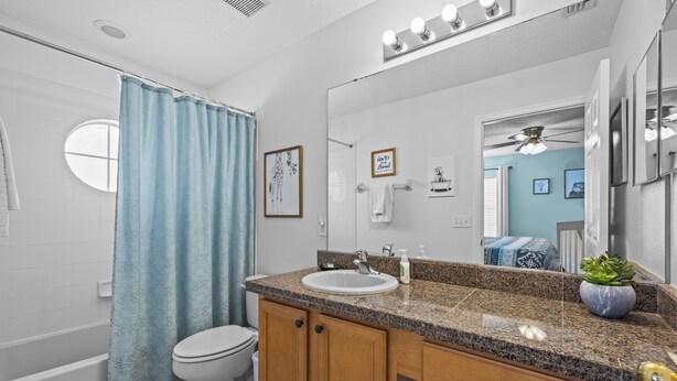 Un baño con lavamanos, inodoro y cortina de ducha.