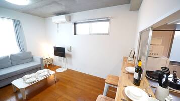 Una sala de estar moderna con un sofá gris, una mesa de centro blanca y un televisor de pantalla plana.