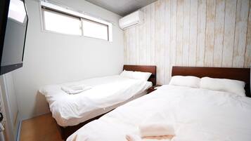 A hotel room with two single beds, a television, and an air conditioning unit.