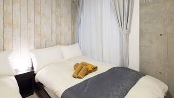 A hotel room with a bed, two nightstands, and a window with curtains.