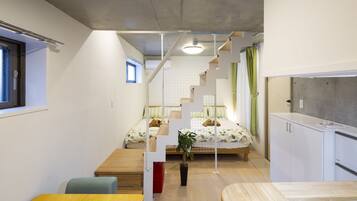 A compact room with a bed, a small table, and a kitchenette area.