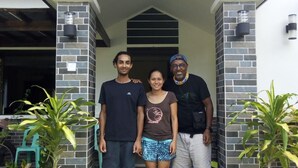 A family standing in front of a house with a stone facade and a wooden roof structure. - Bohol Sweet Home B&B (Guindulman)