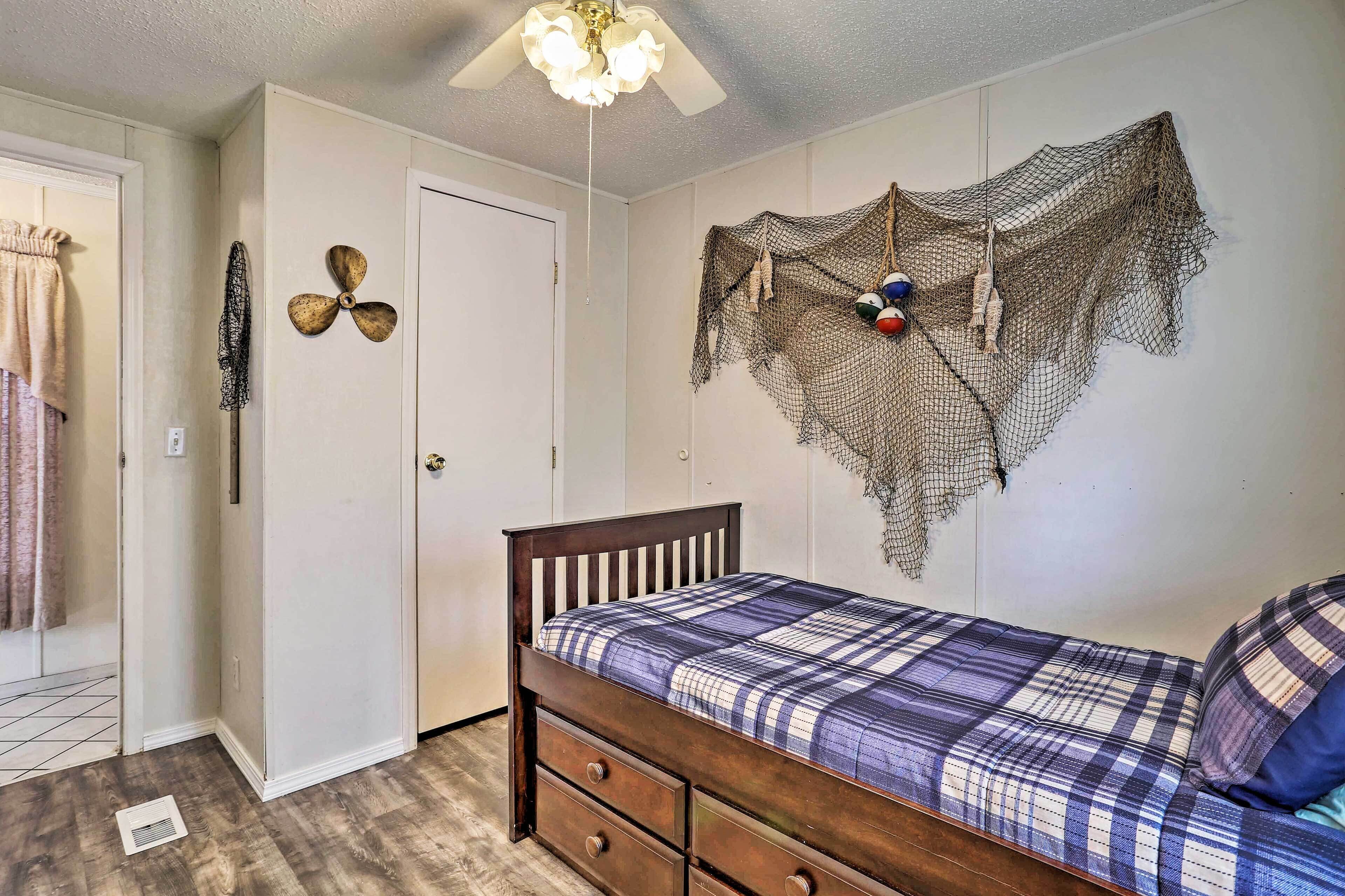 A bedroom with a bed, a ceiling fan, a wall-mounted net, and a door.