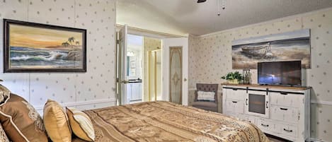 Une chambre à coucher avec un lit, un téléviseur et un ventilateur de plafond.