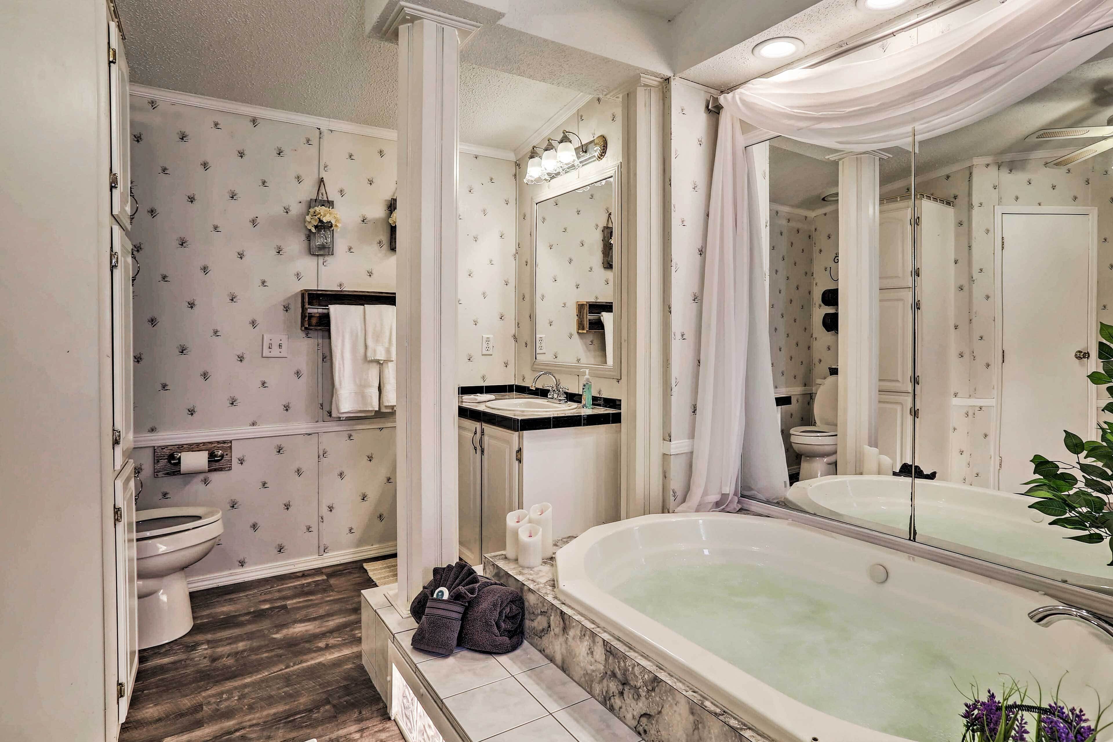 A bathroom with a large bathtub, a toilet, a sink, and a mirror.