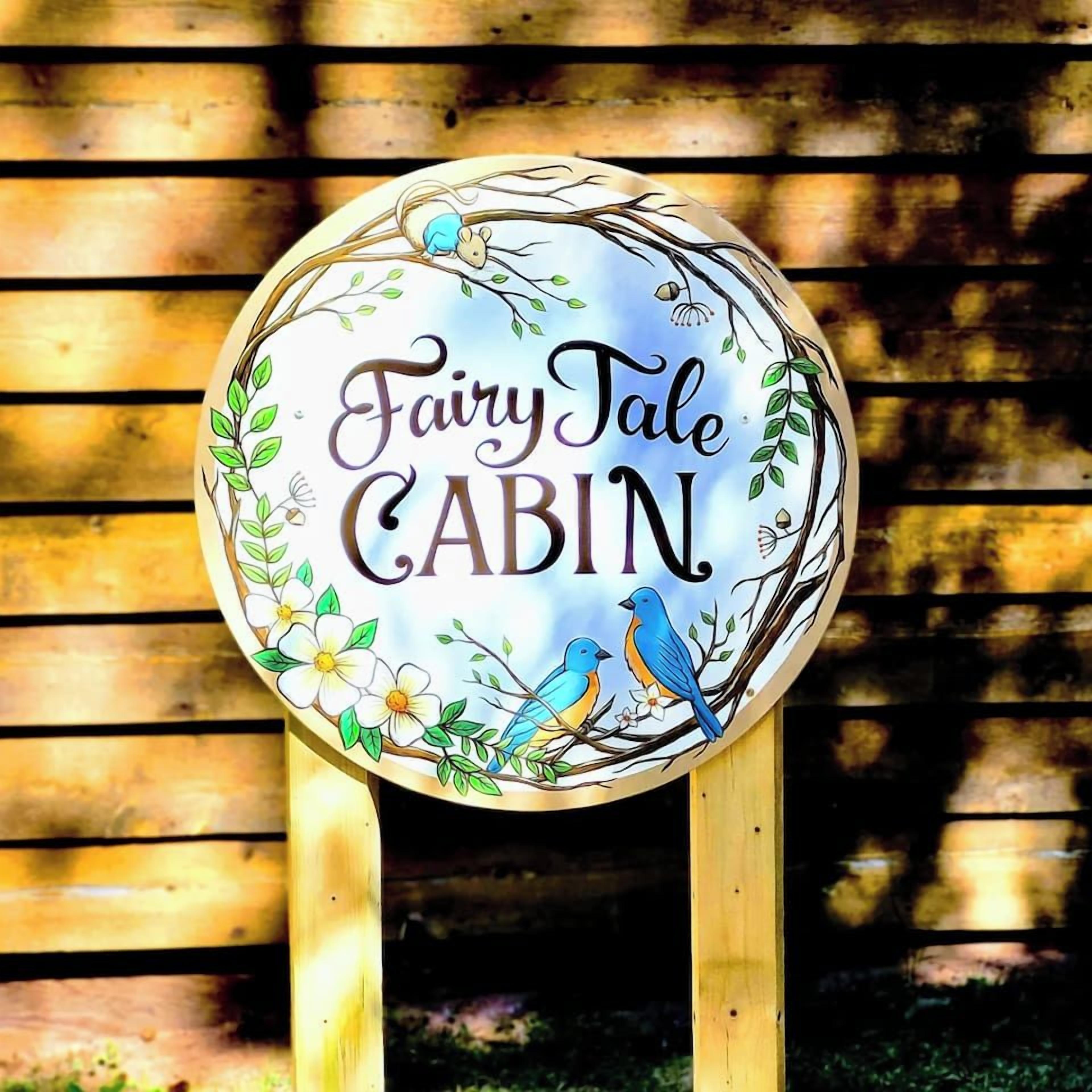 A circular sign with the text 'Fairy Tale Cabin' surrounded by floral and bird illustrations.
