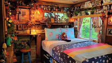 A cozy bedroom with a bed, a stool, and various decorations.