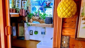 Een smalle trap die leidt naar een badkamer met toilet, plantenplanken en een ananas decoratie.