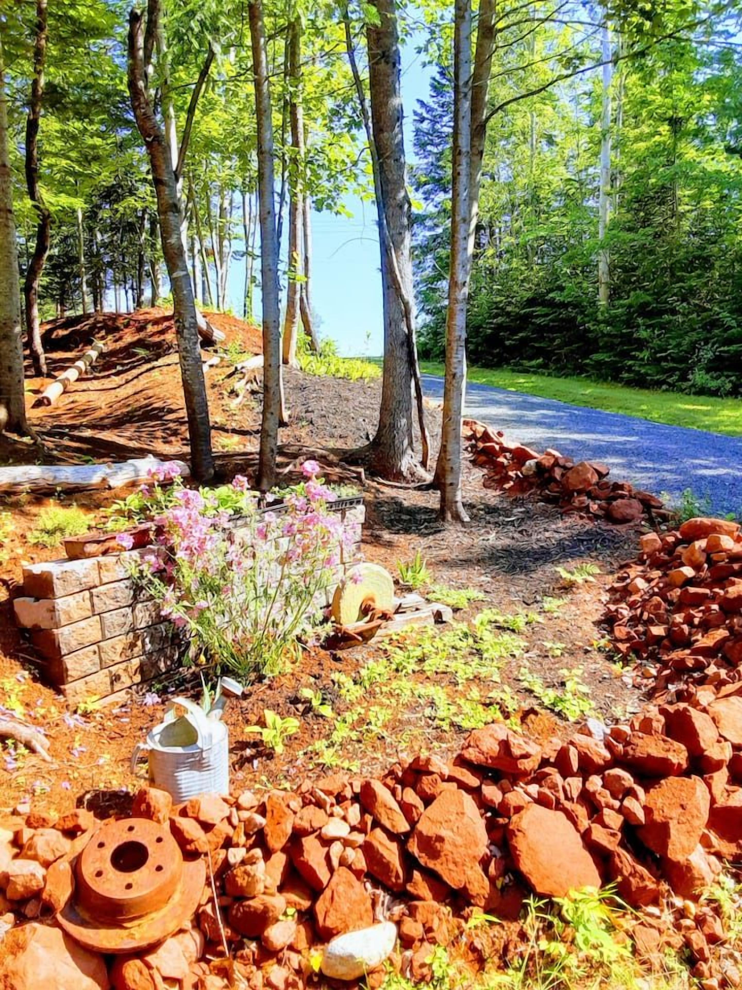 Un espace jardin agrémenté d’arbres, d’un mur en briques et d’un chemin pavé.