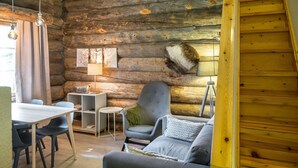 Een gezellig interieur van een chalet met een eethoek, een bank en een lamp.