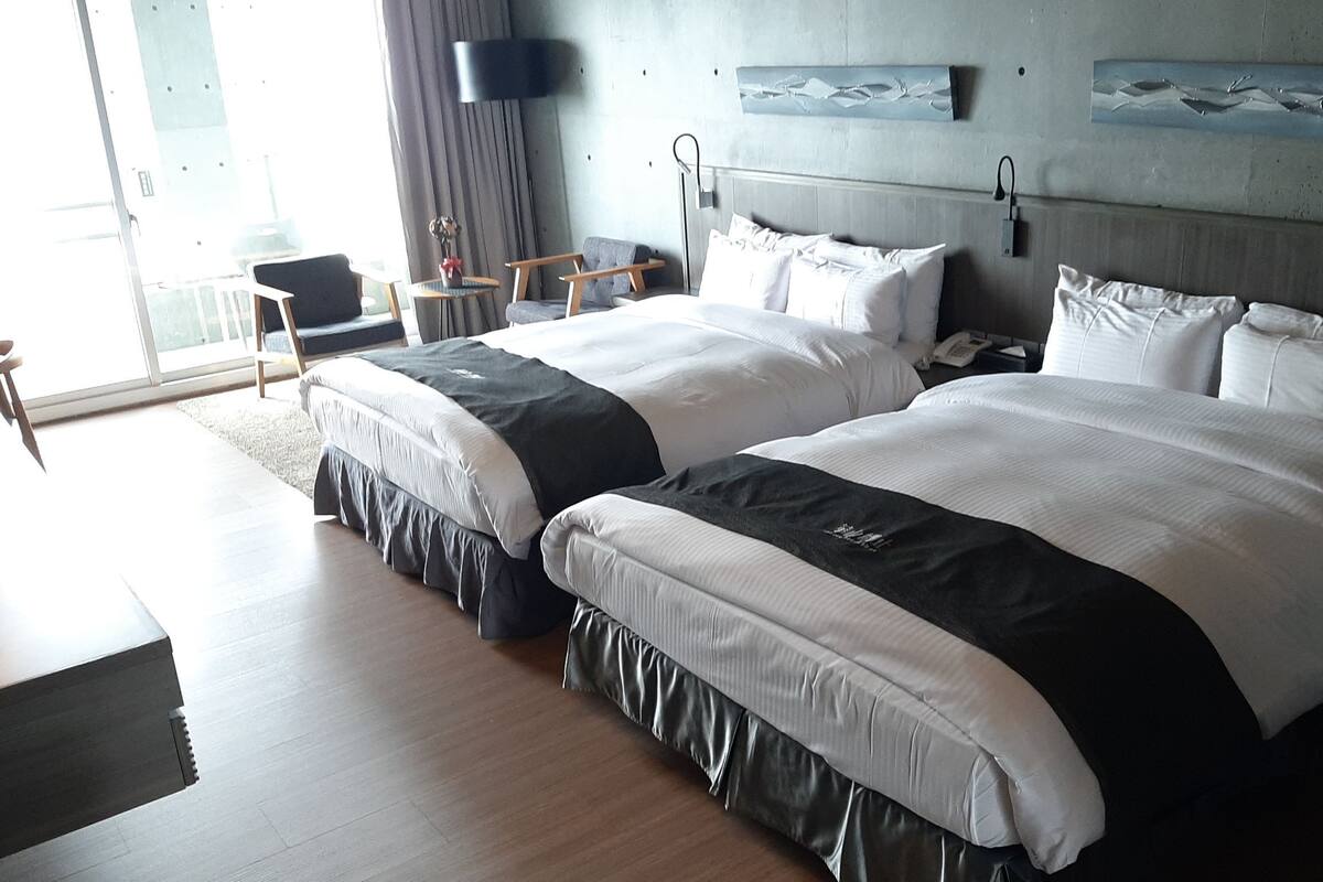 Une chambre d’hôtel avec deux lits, un bureau et une chaise.