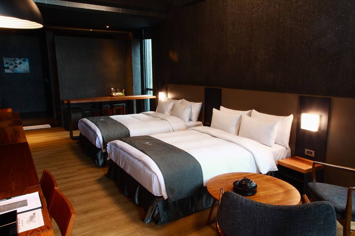 Une chambre d’hôtel avec deux lits, un bureau et une table ronde.
