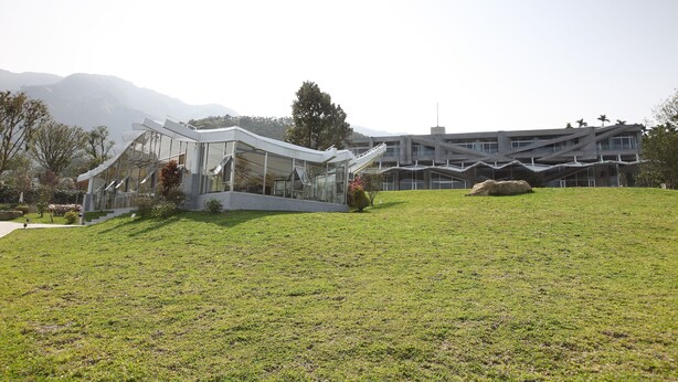 Un edificio moderno con fachada de vidrio y un césped delantero.