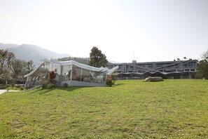 Un bâtiment moderne doté d’une façade en verre et d’une pelouse verdoyante à l’avant.