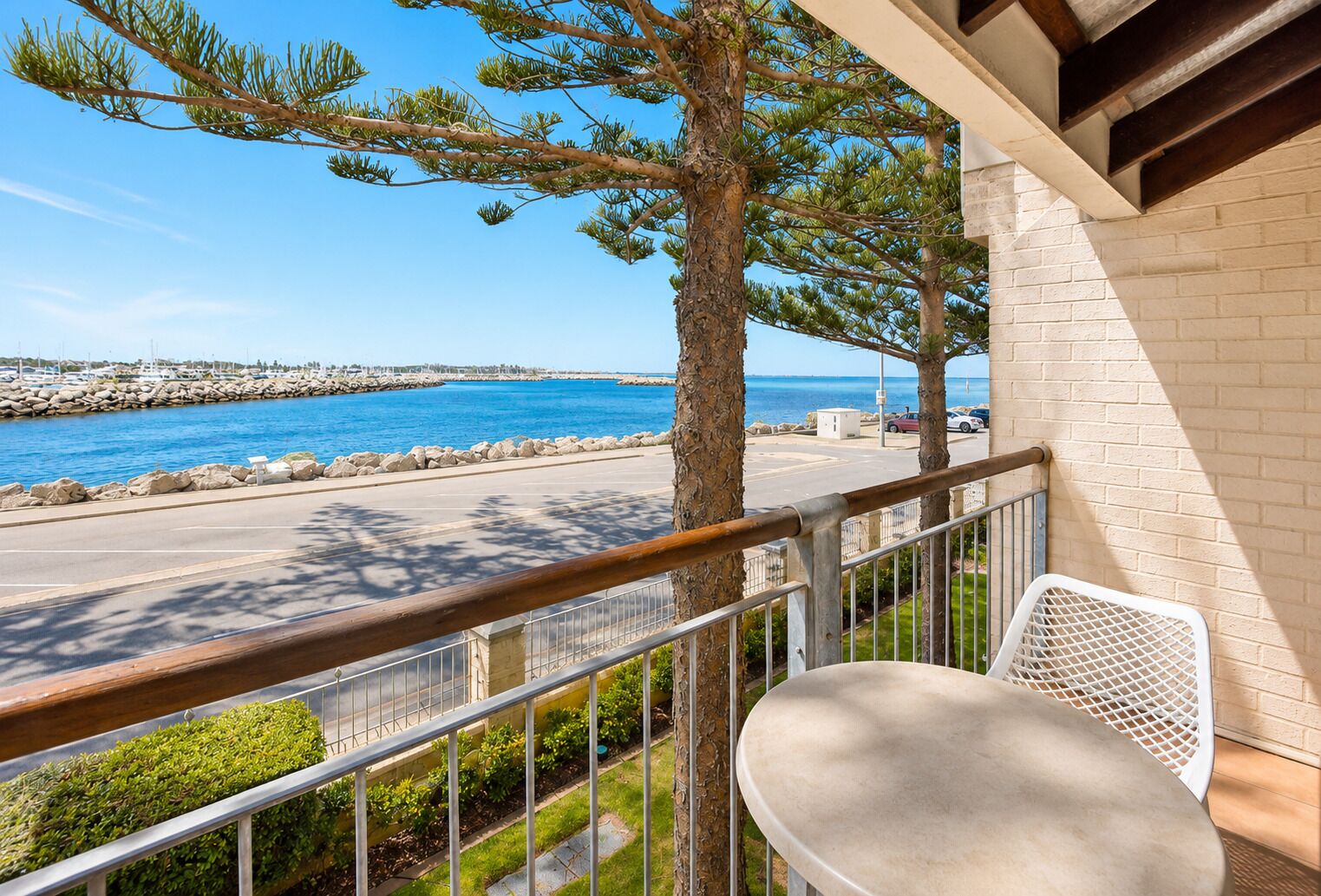 A balcony with a view of the sea, a chair, and a table.