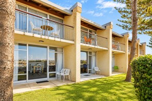 A multi-story building with balconies, large windows, and a grassy courtyard. - Wake up to sweeping harbour views in this modern, split-level apartment located between Fishing Boat Harbour and Challenger Harbour. Whether you're a couple, a family, or here on business, this peaceful retreat offers the best of coastal charm and ci (Fremantle)