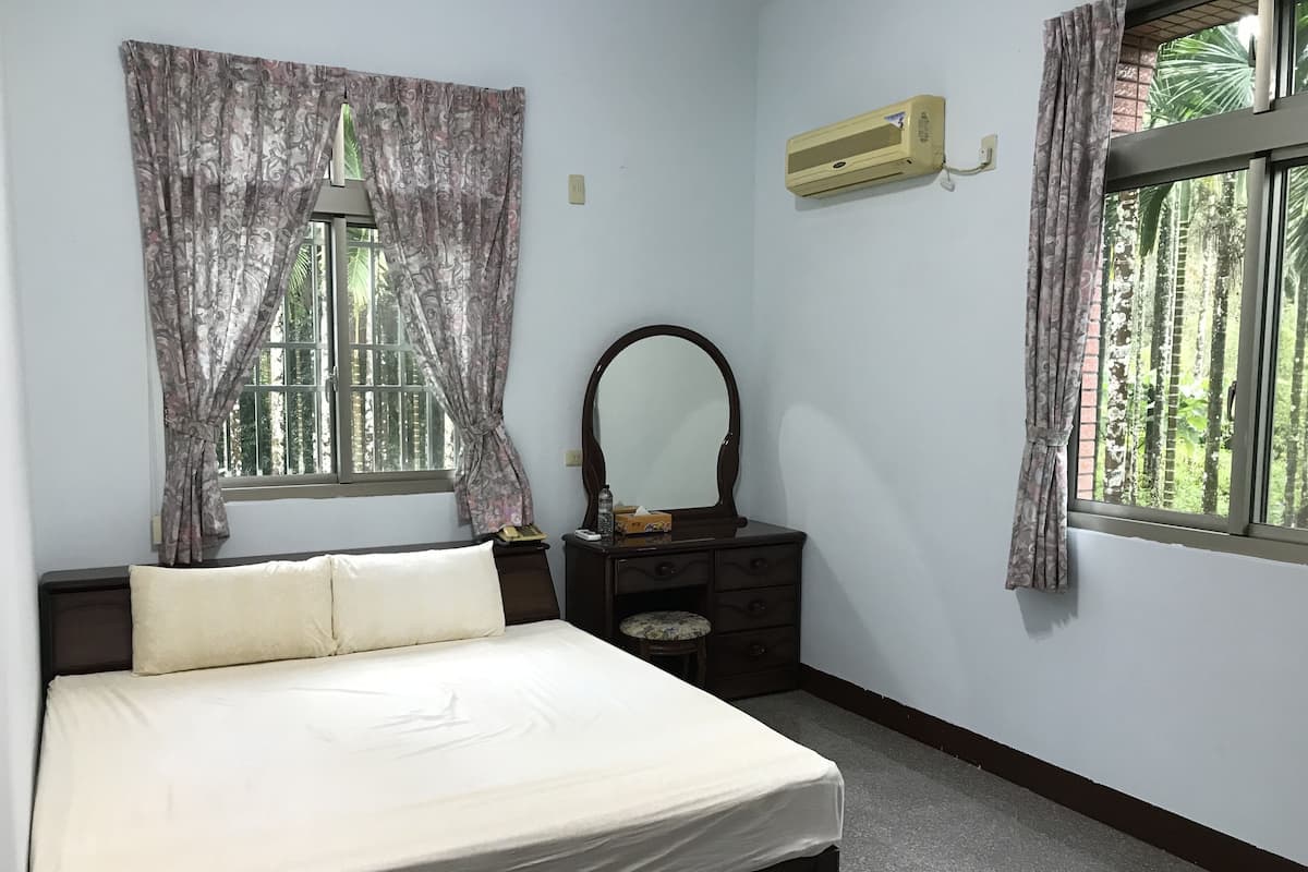 A bedroom with a bed, a dresser, a mirror, and an air conditioning unit.