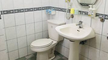 Un baño pequeño con inodoro, lavamanos y espejo.