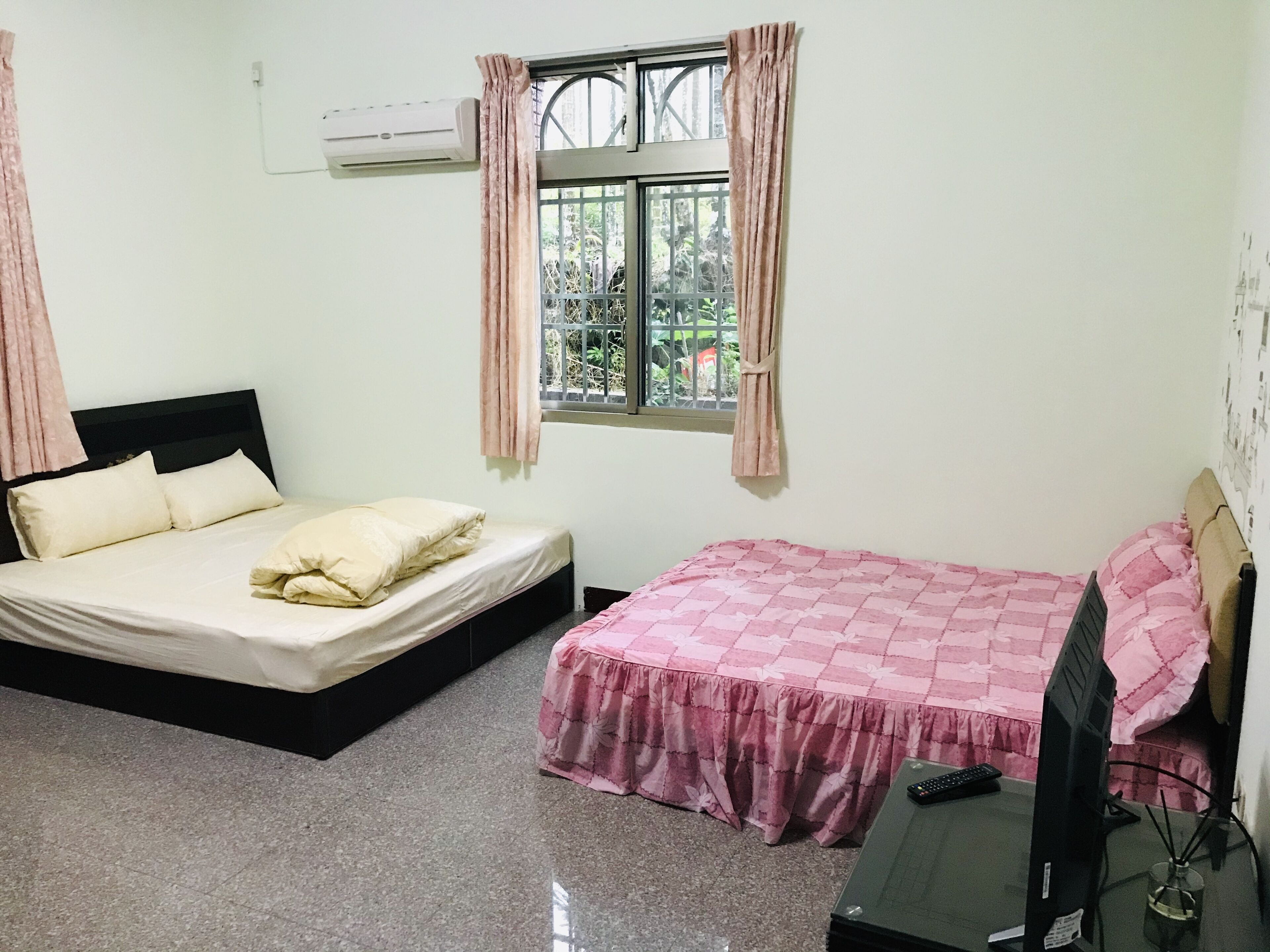 Un dormitorio con dos camas, televisión y aire acondicionado.