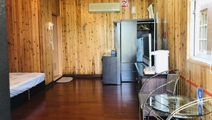 A room with wooden walls, a bed, a desk with a computer, a chair, and a window with curtains. - Hua Yi Homestay (Gukeng)