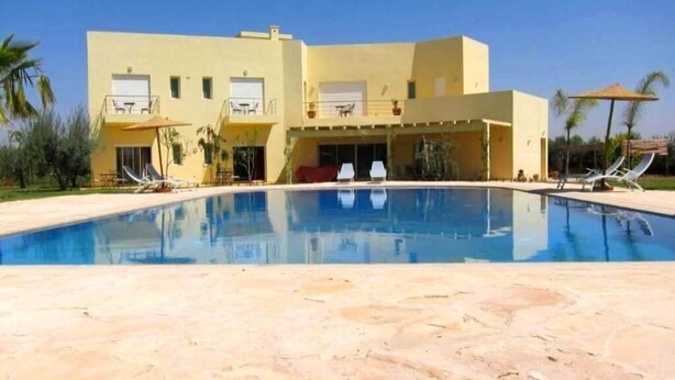 Ein zweistöckiges Gebäude mit einem Pool davor.