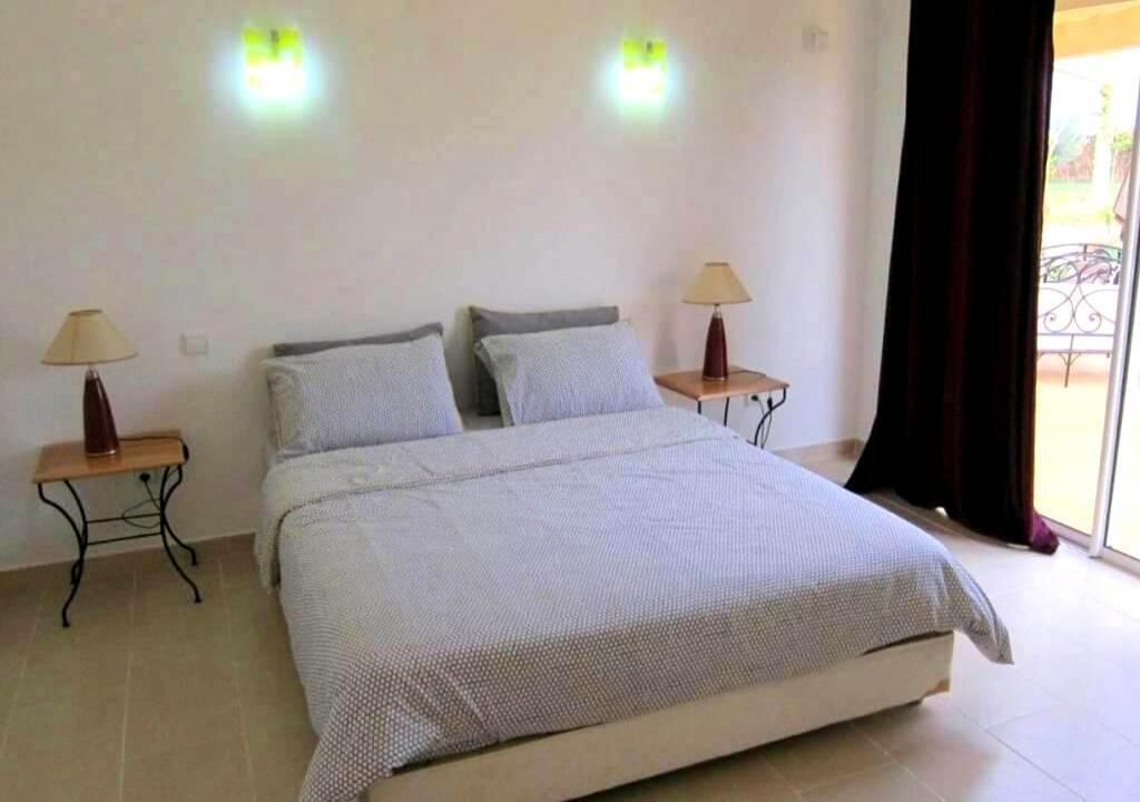 A bedroom with a bed, two bedside tables, and two wall-mounted lamps.