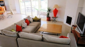 Ein modernes Wohnzimmer mit grauem Sofa, einem Holztisch, einem Fernseher und einer Topfpflanze.