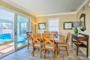 A dining area with a table and chairs, a lamp, a mirror, and a window with blinds. - Oceanside Beach House in Pvt Beach Community! (Mantoloking)