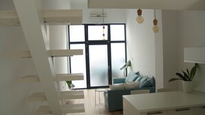 Een moderne woonkamer met een trap, een bank en een eethoek.