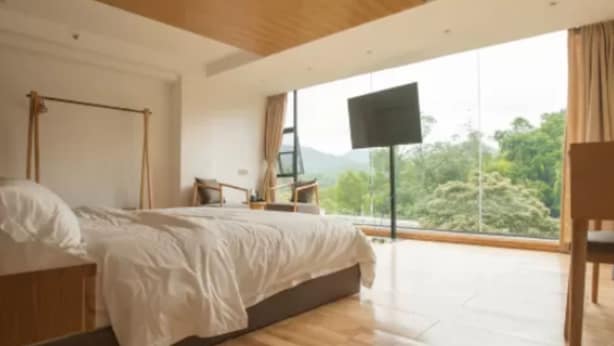 A bedroom with a large bed, a TV, and a view of the outdoors. - Qing Gu Ju (Zhaoqing)