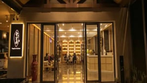 A hotel entrance with a wooden facade, glass doors, and a reception desk visible inside. - Qing Gu Ju (Zhaoqing)