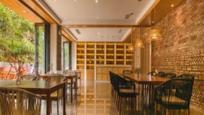A restaurant with a brick wall, wooden tables, and chairs. - Qing Gu Ju (Zhaoqing)