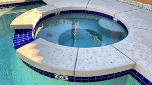 A hot tub with a tiled edge and a surrounding pool area. - Serene Desert Escape-Salt Water Pool & Jacuzzi/Fire Pit/Views #067047 3bd (La Quinta)