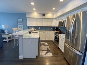 Una cucina moderna con mobili bianchi, un frigorifero in acciaio inossidabile e un forno a microonde integrato.