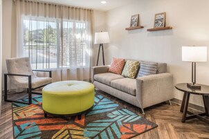 Una sala de estar con sofá, sillón, reposapiés y dos lámparas.