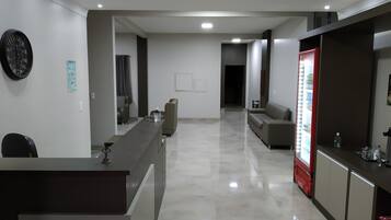 Un moderno vestíbulo de hotel con mostrador de recepción, zona de estar y un refrigerador.