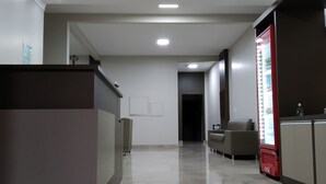 Un lobby moderno con una recepción, un área de descanso y un refrigerador lleno de bebidas.