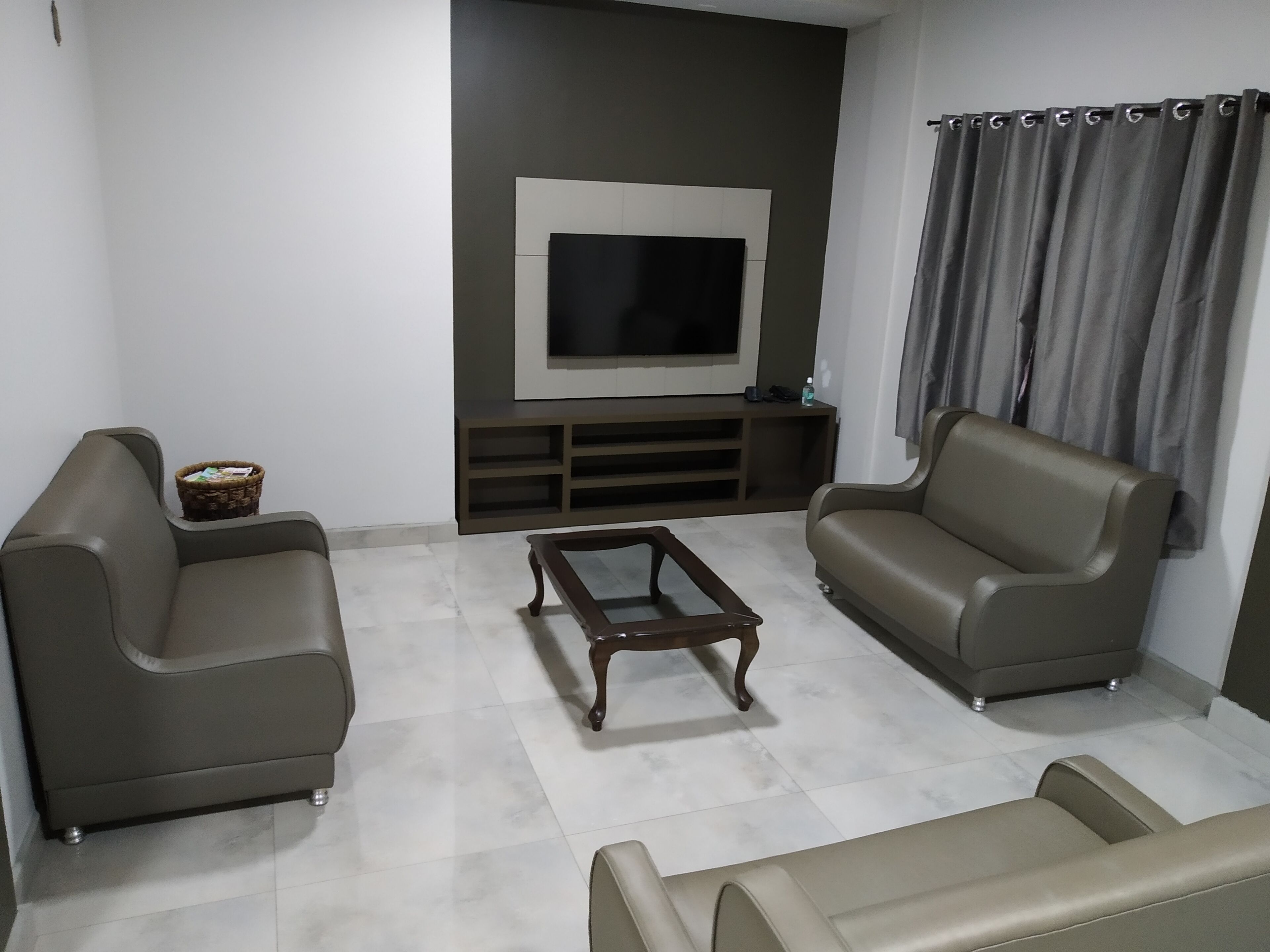 A modern living room with two sofas, a coffee table, and a TV on a wall.