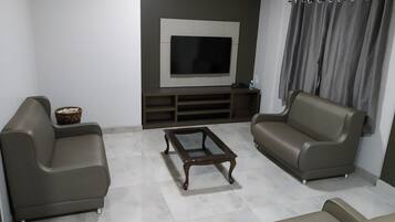 A modern living room with two sofas, a coffee table, and a TV on a wall.