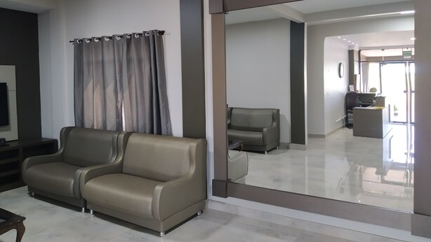 Una sala moderna con un sofá, una televisión y un espejo grande que refleja la habitación.