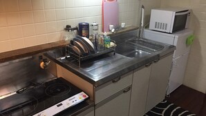 A compact kitchen with a stove, sink, and microwave. - ASHITOMI HOUSE (南城市)