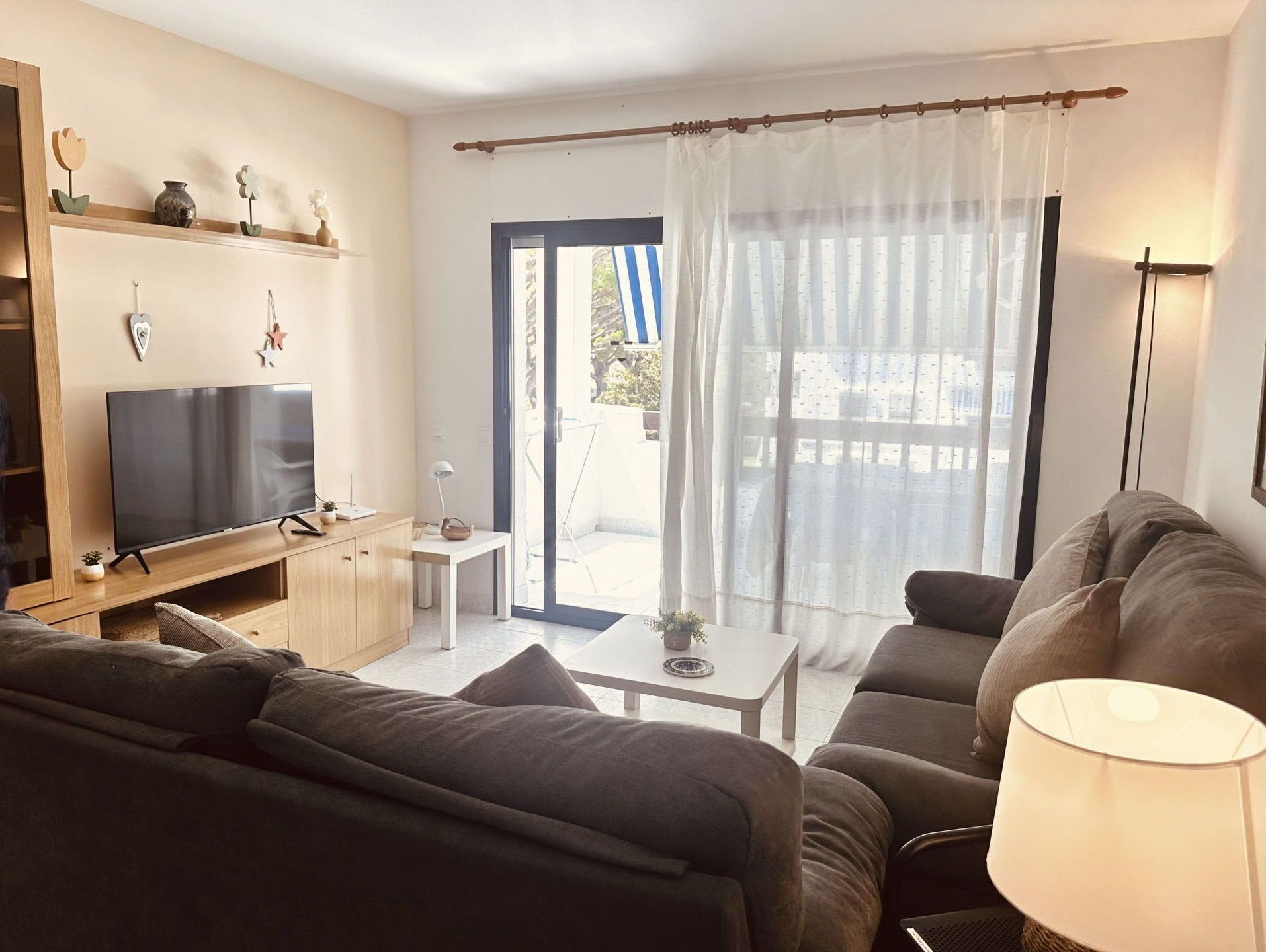 Un salon avec un canapé, un téléviseur, une petite table et une lampe.