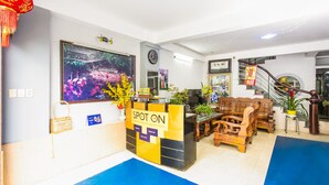 A hotel reception area with a reception desk, wooden furniture, a clock, and a large framed picture on the wall.