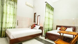 A room with two wooden beds, a wooden table, and a chair.