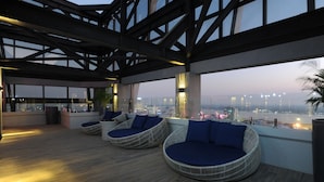 A rooftop lounge with wicker chairs and a city view. - Yangon Thanlwin Hotel (Yangon)